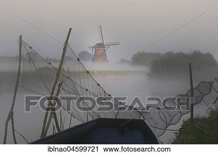 Fish trap in front of historical windmill in early mist, UNESCO World Heritage Site, Kinderdijk, province of South Holland, Netherlands View Large Photo Image Stock Image - Fish trap in front of historical windmill in early mist, UNESCO World Heritage Site, Kinderdijk, province of South Holland, Netherlands. Fotosearch