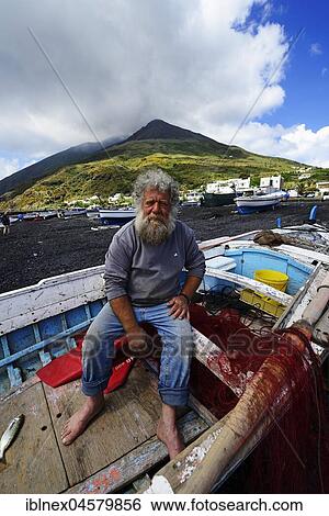 Stock Photograph - Fisherman in his boat in front of volcano on Scari beach, Stromboli Island, Liparic Islands, Italy, Europe. Fotosearch