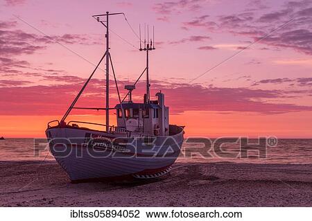 Stock Image - Fishing boat on the beach at sunset, Vorupör, Nordjylland, Denmark, Europe. Fotosearch