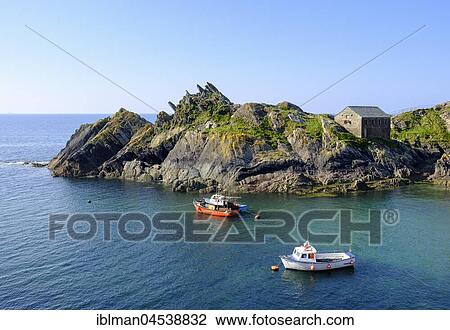 Stock Image - Fishing boats, Chapel Rock and Net Loft, cliffs on coast in Polperro, Cornwall, England, United Kingdom, Europe. Fotosearch