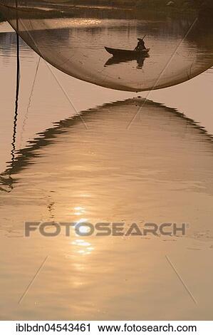 Stock Image - Fishing net and boatman, River Thu Bon, Hoi An, Vietnam, Asia. Fotosearch