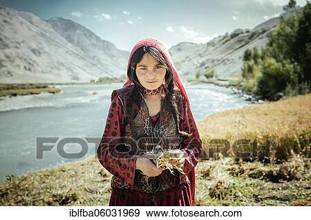 Stock Photo - Girl, 8 years, bundles small wheat yarbs, members of the ethnic group of the sedentary Wakhi, Khandud, Wakhan Corridor, Afghanistan, Asia. Fotosearch