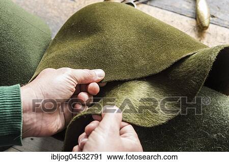 Stock Image - Hands checking different wool felt hat bodies, shades of green, on workbench, hatmaker workshop, Bad Aussee, Styria, Austria, Europe. Fotosearch