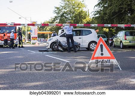 Stock Image - Heavy road accident, Simson scooter crashing in car, policewoman at place of accident, Germany, Europe. Fotosearch