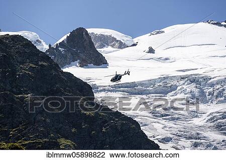 Stock Image - Helicopter flies over glaciers, alpine rescue, mountain rescue, Mont Blanc massif, Chamonix, Haute-Savoie, France, Europe. Fotosearch