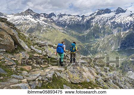 Stock Photography - Hiker on marked hiking trail, descent from Schönbichler Horn to Berliner Hütte, behind Schwarzenstein and the Schwarzensteinkees glacier, Berliner Höhenweg, Zillertal Alps, Zillertal, Tyrol, Austria, Europe. Fotosearch