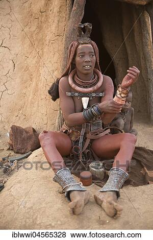 Stock Photo - Himba woman with child in front of the hut, rubs itself with Okra, butterfat with ochre paint, Kaokoveld, Namibia, Africa. Fotosearch