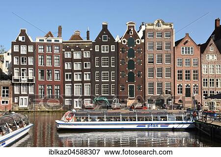 Historic buildings and boat for canal cruise on the Damrak, Amsterdam, North Holland, Holland, Netherlands View Large Photo Image Stock Photo - Historic buildings and boat for canal cruise on the Damrak, Amsterdam, North Holland, Holland, Netherlands. Fotosearch