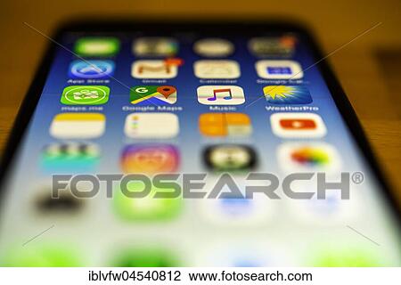 Stock Image - IPhone lying on table, luminous display, screen, iPhone, many different app icons, app, cell phone, smartphone, iOS, macro shot, detail, full frame. Fotosearch