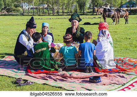 Stock Photography - Kazakh family in traditional clothes praying before lunch, Sati village, Tien Shan Mountains, Kazakhstan, Asia. Fotosearch
