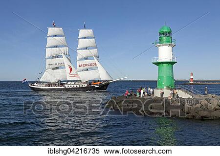 Stock Photography - Lighthouse with sailing boat Mercedes at back, Hanse Sail, harbour entrance, port entrance Warnemünde, Mecklenburg-Western Pomerania, Germany, Europe. Fotosearch