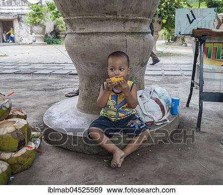 Little Indonesian boy eating grilled corn on the road side, Yogyakarta, Java, Indonesia, Asia View Large Photo Image Stock Photo - Little Indonesian boy eating grilled corn on the road side, Yogyakarta, Java, Indonesia, Asia. Fotosearch