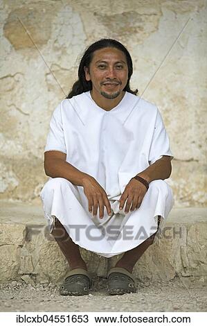 Stock Image - Man, 36 years old, Lacandone ethnic group, sitting at the wall, in traditional white Mayan dress for men, Selva Lacandona, Chiapas, Mexico, Central America. Fotosearch