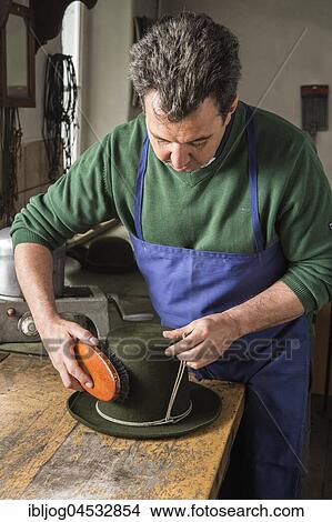 Picture - Man brushing a dry wool felt hat, holding shaping cord in his hand, hatmaker workshop, Bad Aussee, Styria, Austria, Europe. Fotosearch