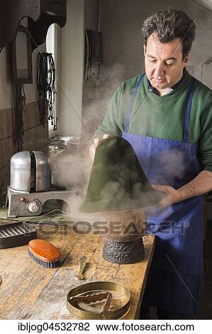 Stock Image - Man fitting wet hat body to wooden form, hatmaker workshop, Bad Aussee, Styria, Austria, Europe. Fotosearch