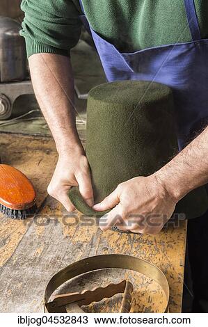 Stock Image - Man fitting wet hat body to wooden form, hatmaker workshop, Bad Aussee, Styria, Austria, Europe. Fotosearch
