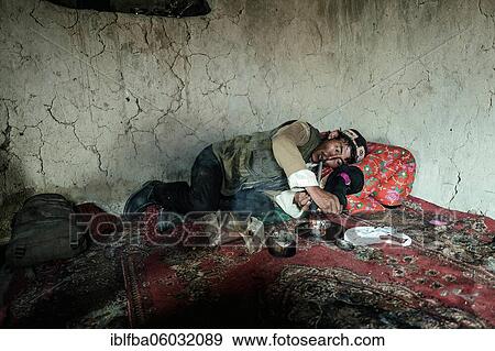 Stock Photo - Man lying on a carpet, pulling an opium pipe, Bozai Gumbaz, Wakhan Corridor, Badakhshan, Afghanistan, Asia. Fotosearch