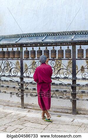 Stock Image - Monk turning Prayer Wheels, Swayambunath or Monkey Temple, Unesco World Heritage Site, Kathmandu, Nepal, Asia. Fotosearch
