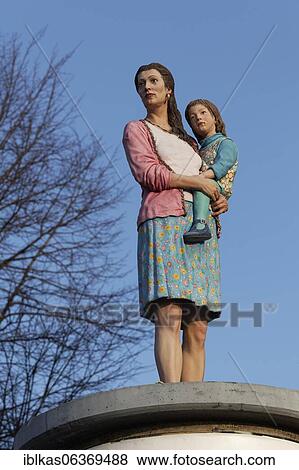 Stock Photo - Mother with child in her arms, realistic figure on an advertising pillar, column saint, sculpture by Christoph Pöggeler, Düsseldorf, North Rhine-Westphalia, Germany, Europe. Fotosearch