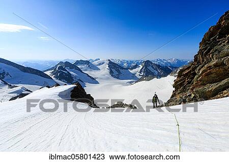 Stock Image - Mountaineer on a high climb on a long rope over a snowfield on the Altmann, Canton Valais, Switzerland, Europe. Fotosearch