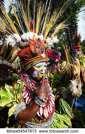 Stock Image - Native inhabitants of the highland tribe Marowa Welda, in costume, with headdress, painted, smoking, Sing-Sing Festival, Goroka, Papua New Guinea, Oceania. Fotosearch