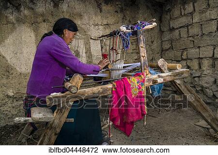 Stock Image - Native woman weaving material on loom, open air, Jhong, Mustang District, Nepal, Asia. Fotosearch