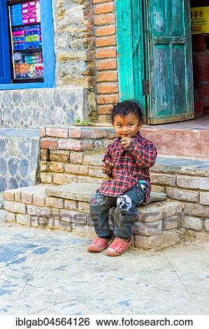 Stock Photograph - Nepalese boy sitting on stairs, Bandipur, Tanahun district, Nepal, Asia. Fotosearch
