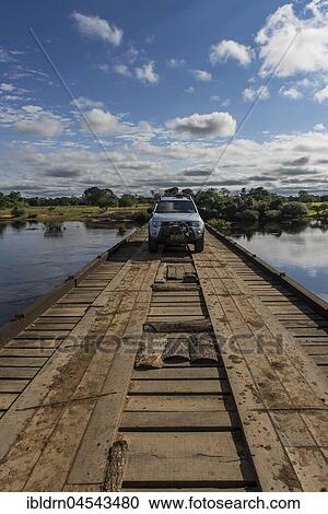 Stock Image - Off road vehicle driving across wooden bridge, Rio, Pantanal, Mato Grosso do Sul, Brazil, South America. Fotosearch
