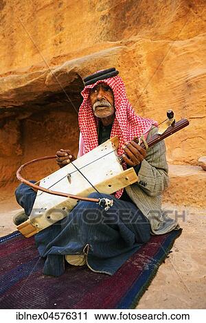 Stock Image - Old bedouin playing the one-string Lyra, Little Petra, Jordan, Asia. Fotosearch