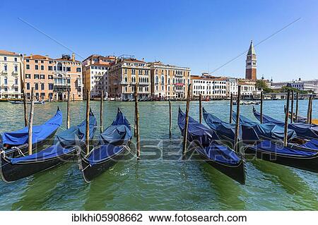 Stock Image - Parking gondolas in the Canale Grande, behind them historic house facades and the Campanile San Marco, Venice, Veneto, Italy, Europe. Fotosearch