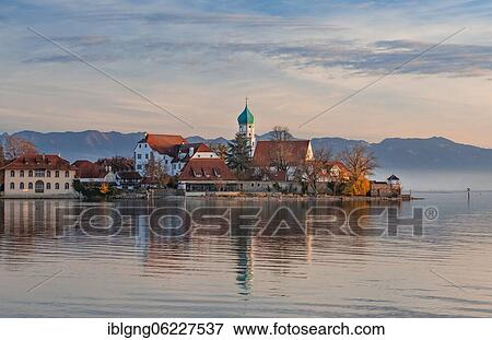 Peninsula with the parish church of St. George in front of the Alps in the evening sun, moated castle on Lake Constance, Swabia, Bavaria, Germany, Europe View Large Photo Image Stock Photo - Peninsula with the parish church of St. George in front of the Alps in the evening sun, moated castle on Lake Constance, Swabia, Bavaria, Germany, Europe. Fotosearch