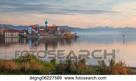 Peninsula with the parish church of St. George in front of the Alps in the evening sun, moated castle on Lake Constance, Swabia, Bavaria, Germany, Europe View Large Photo Image Stock Photo - Peninsula with the parish church of St. George in front of the Alps in the evening sun, moated castle on Lake Constance, Swabia, Bavaria, Germany, Europe. Fotosearch