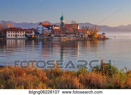 Peninsula with the parish church of St. George in front of the Alps in the evening sun, moated castle on Lake Constance, Swabia, Bavaria, Germany, Europe View Large Photo Image Stock Photo - Peninsula with the parish church of St. George in front of the Alps in the evening sun, moated castle on Lake Constance, Swabia, Bavaria, Germany, Europe. Fotosearch