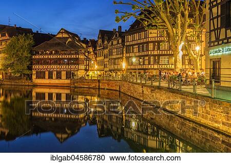 Stock Image - People on a restaurant terrace along the ILL canal at twilight, Strasbourg, Alsace, Bas-Rhin Department, France, Europe. Fotosearch