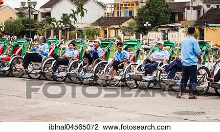 Stock Image - Rickshaw riders sit in their bicycle rickshaws at the roadside, Hoi An, Vietnam, Asia. Fotosearch