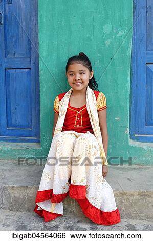 Stock Photograph - Smiling Nepalese girl seated on steps in front of a colorful house, Bandipur, Tanahun district, Nepal, Asia. Fotosearch