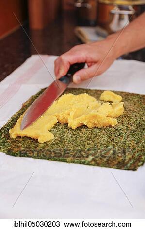 Stock Image - South German cuisine, preparation of polenta spinach roulade, handing out polenta with knife, Germany, Europe. Fotosearch