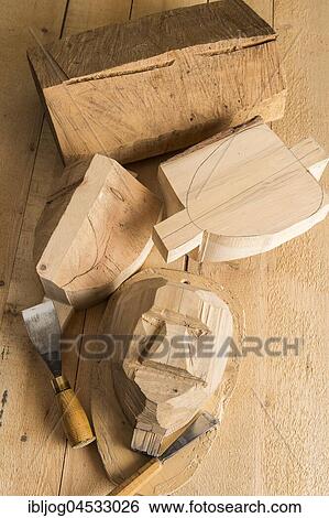 Stock Photograph - Steps from wooden block to wooden mask, wooden block and unfinished masks on workbench with wood carving tools, wooden mask carver, Bad Aussee, Styria, Austria, Europe. Fotosearch