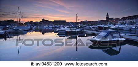 Stock Image - Sunset, historic centre and boats are reflected in the city harbor, Waren-Müritz, Mecklenburg-Western Pomerania, Germany, Europe. Fotosearch