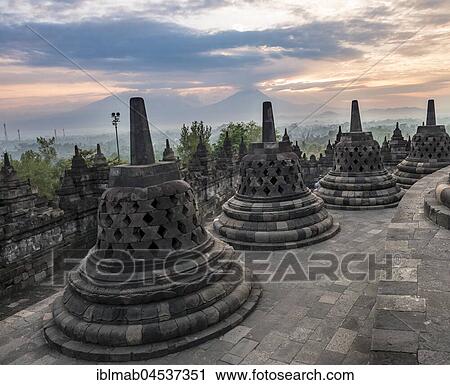 Stock Image - Temple complex Borobudur at sunrise, Stupas, cloudy sky, Borobudur, Yogyakarta, Java, Indonesia, Asia. Fotosearch