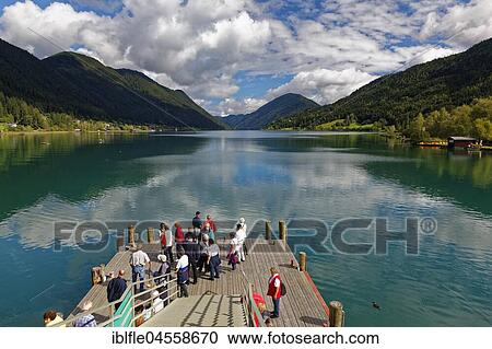 Stock Image - Tourists waiting at the jetty, Weißensee, Carinthia, Austria, Europe. Fotosearch