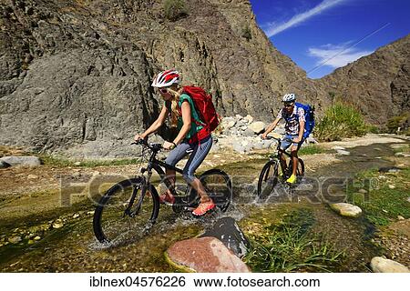 Stock Photograph - Tourists with mountain bikes in the area of Feynan Ecolodge, Jordan, Asia. Fotosearch