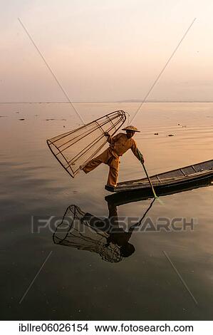 Traditional fisherman posing standing on his small boat in front of sunrise, Lake Inle, Myanmar, Asia View Large Photo Image Picture - Traditional fisherman posing standing on his small boat in front of sunrise, Lake Inle, Myanmar, Asia. Fotosearch