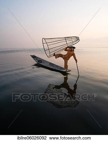 Traditional fisherman posing standing on his small boat with reflection in front of sunrise, Lake Inle, Myanmar, Asia View Large Photo Image Stock Image - Traditional fisherman posing standing on his small boat with reflection in front of sunrise, Lake Inle, Myanmar, Asia. Fotosearch