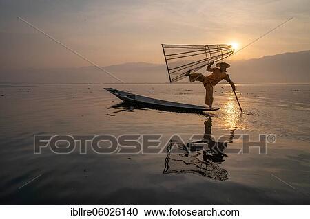 Traditional fisherman posing standing on his small boat in front of sunrise, Lake Inle, Myanmar, Asia View Large Photo Image Stock Image - Traditional fisherman posing standing on his small boat in front of sunrise, Lake Inle, Myanmar, Asia. Fotosearch