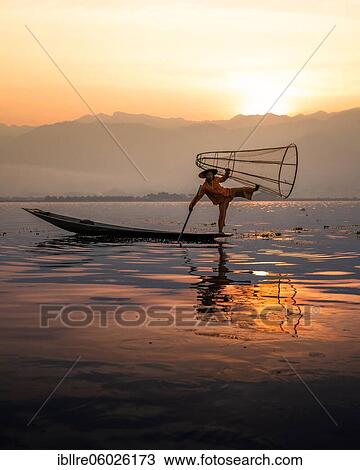 Traditional fisherman posing standing on his small boat in front of sunrise, Lake Inle, Myanmar, Asia View Large Photo Image Stock Image - Traditional fisherman posing standing on his small boat in front of sunrise, Lake Inle, Myanmar, Asia. Fotosearch