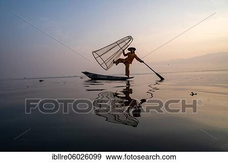 Traditional fisherman posing standing on his small boat with reflection in front of sunrise, Lake Inle, Myanmar, Asia View Large Photo Image Stock Photo - Traditional fisherman posing standing on his small boat with reflection in front of sunrise, Lake Inle, Myanmar, Asia. Fotosearch