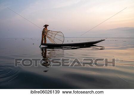 Traditional fisherman posing standing on his small boat in front of sunrise, Lake Inle, Myanmar, Asia View Large Photo Image Stock Photo - Traditional fisherman posing standing on his small boat in front of sunrise, Lake Inle, Myanmar, Asia. Fotosearch