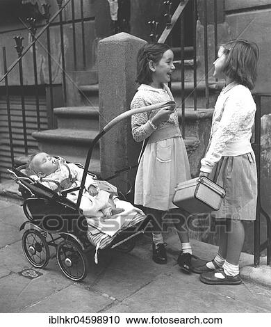Stock Image - Two girls with baby and prams, England, Great Britain. Fotosearch