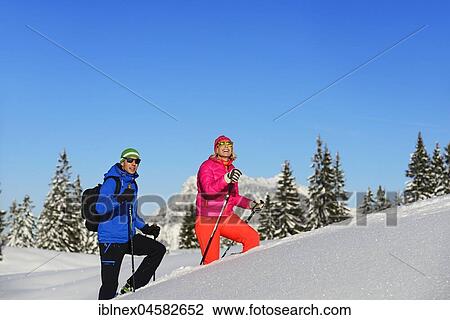 Stock Image - Two hikers walk through deep snow, premium winter hiking trail, Hemmersuppenalm, Reit im Winkl, Chiemgau, Oberbayern, Bavaria, Germany.. Fotosearch